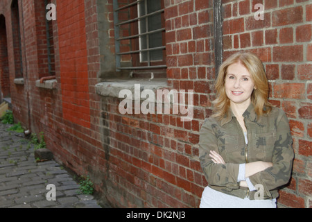 Femme à côté de Red Brick Warehouse smiling Banque D'Images