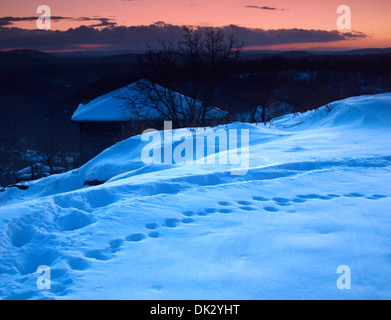 Petit chalet en bois dans les montagnes couvertes de neige au crépuscule Banque D'Images