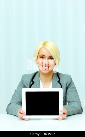 Happy businesswoman showing écran d'un tablet computer in office Banque D'Images