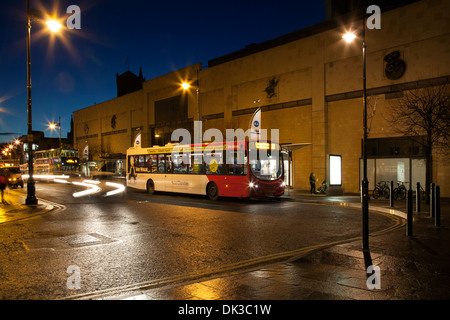 Scène de nuit pluvieuse, l'éclairage des rues et les transports publics de la ville de Dundee. Le terminus de bus National Express dans la pluie au crépuscule, Ecosse, Royaume-Uni Banque D'Images