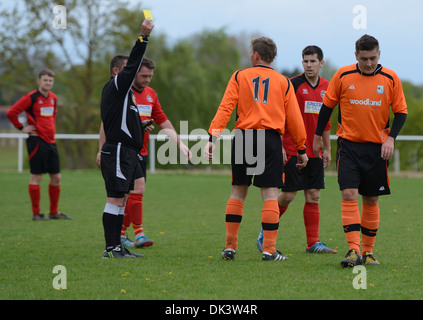 Carton jaune brandi par l'arbitre pour jeu déloyal au football club Foxash,Lawford,Essex,UK Banque D'Images