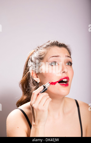 Jeune femme rouge à lèvres frottis sur son visage Banque D'Images