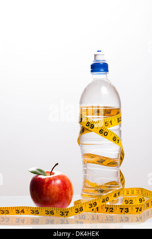 Pomme rouge et une bouteille d'eau entouré de ruban de mesure Banque D'Images