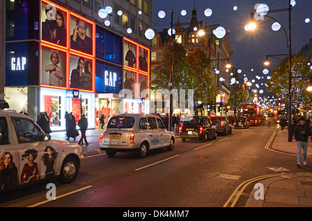 Oxford Street West End de Londres taxis faisant la queue dans la scène de rue commerçante devant le magasin de vêtements Gap nuit illuminé décorations de Noël Angleterre Royaume-Uni Banque D'Images