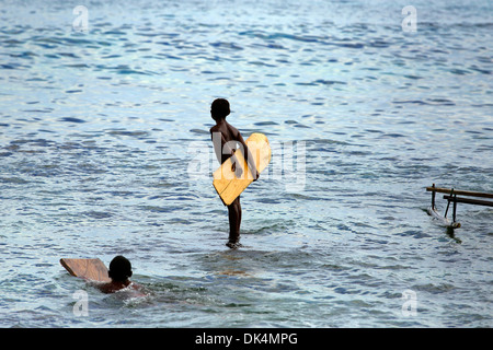 Les garçons papou avec des morceaux de bois utilisés comme des planches de vagues d'attente Banque D'Images
