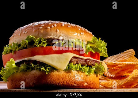 Burger avec des frites se concentrer sur fond noir en avant. Banque D'Images