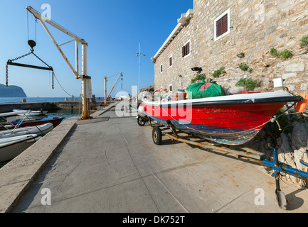 Bateau de pêche rouge se dresse sur la côte, dans le port de Petrovac, Monténégro Banque D'Images