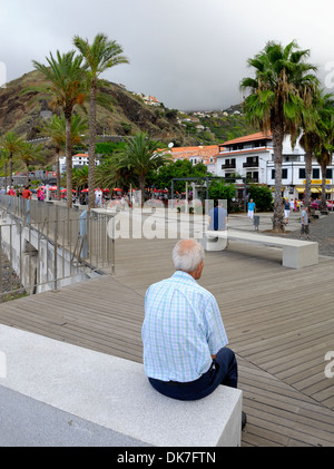 Ribeira Brava Portugal Madère. Un homme âgé assis sur un banc en béton sur le front de mer Banque D'Images