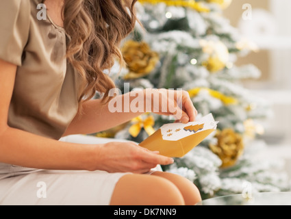 Gros plan sur young woman opening christmas lettre near Christmas Tree Banque D'Images