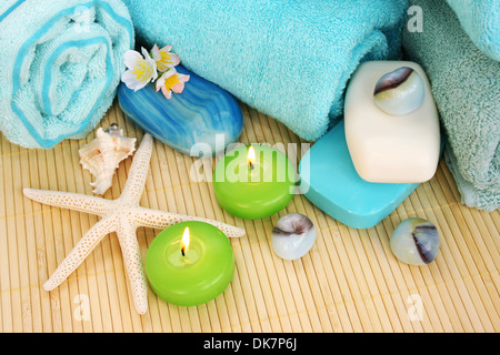 Pile de serviettes, savons, bougies, pierres, fleurs sur fond mat. Banque D'Images