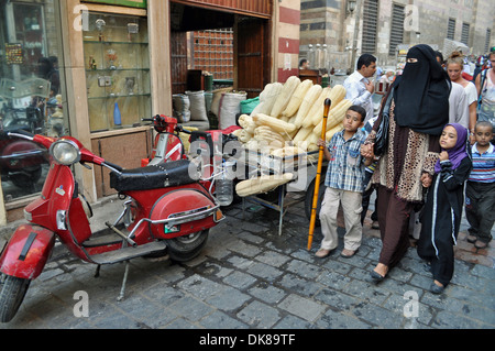 Une femme dans un niqab associée à une tenue moderne conduit deux de ses enfants à travers le quartier islamique de la capitale égyptienne le Caire. Banque D'Images