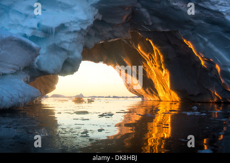 L'Antarctique, l'Île Petermann, l'établissement le soleil de minuit brille à travers l'arc de la fonte iceberg près de Canal Lemaire Banque D'Images