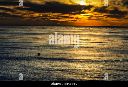 Un surfeur solitaire dans l'océan Pacifique pendant le coucher du soleil. Photographié de Sunset Cliffs Natural Park, San Diego, Californie, USA. Banque D'Images