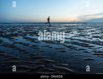 Jogger sur Seaton Carew plage à sunrisein l'hiver. Seaton Carew près de Hartlepool, Angleterre, RU Banque D'Images