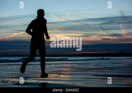Jogger sur Seaton Carew plage à sunrisein l'hiver. Seaton Carew près de Hartlepool, Angleterre, RU Banque D'Images