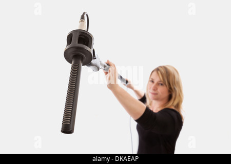 Femme tenant un microphone sur un arrière-plan. Selective focus sur le microphone, le mont. Banque D'Images