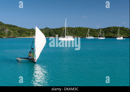 Meli (man sur helm) et une voile Jiko voilier traditionnel, un camakau, bateaux de croisière passé ancré dans Fulaga lagoon, Fidji Banque D'Images