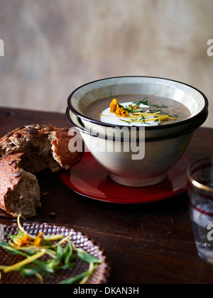 Table avec bol de soupe aux champignons et à l'estragon et le pain brun Banque D'Images