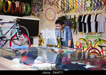 Jeune homme dans le magasin de vélo à l'aide d'ordinateur Banque D'Images