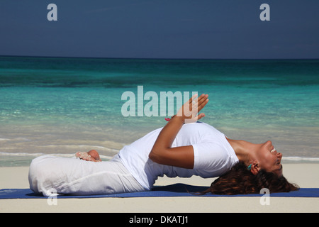 Young woman on beach faisant du yoga, Paradise Island, Nassau, Bahamas Banque D'Images