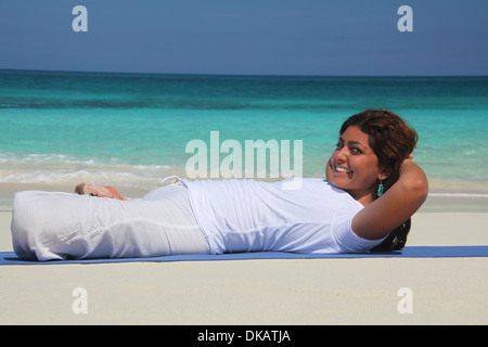 Young woman on beach pratiquant le yoga, Paradise Island, Nassau, Bahamas Banque D'Images