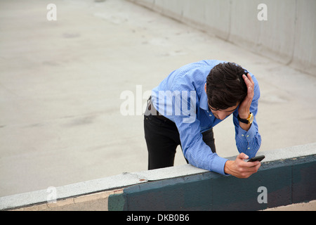 Anxieux young man leaning on wall on city rooftop Banque D'Images