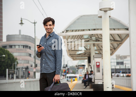 Man with mobile phone à la station, Los Angeles, Californie, USA Banque D'Images
