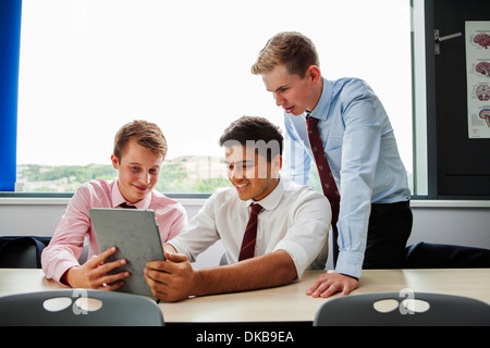 Les collégiens sitting at desk with digital tablet Banque D'Images