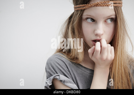 Portrait of Girl wearing tresse cuir autour de tête, holding feather, finger in mouth Banque D'Images