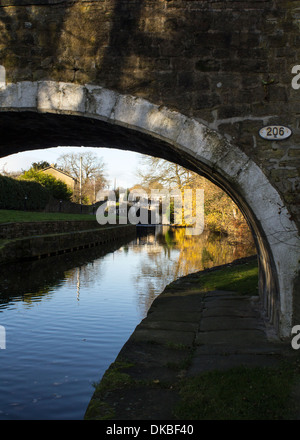 La mise en miroir de l'eau l'automne ciel et des couleurs vives, souligné par un beau sentier pont de pierre à l'eau du canal de Bradford Banque D'Images