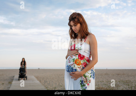 Pregnant woman standing on boardwalk, femme poussant poussette en arrière-plan Banque D'Images