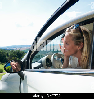 Young woman applying make up en miroir de voiture Banque D'Images