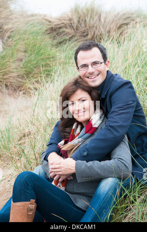 Portrait of couple sitting on sand dune Banque D'Images