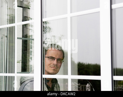 Portrait of mid adult man looking out of window Banque D'Images