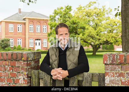 Mid adult man leaning on wooden gate Banque D'Images