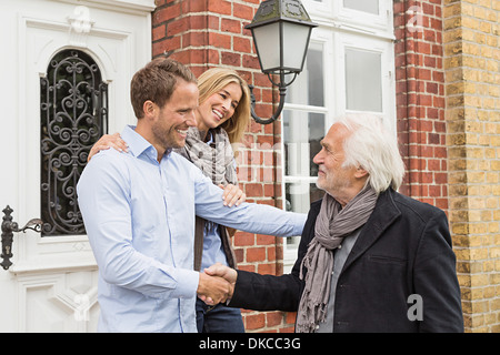 Couple par porte avant, senior man shaking hands Banque D'Images