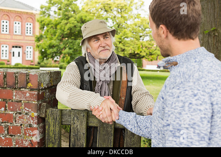 Man man shaking hands over gate Banque D'Images