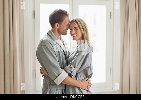 Portrait of mid adult couple wearing robes, hugging Banque D'Images