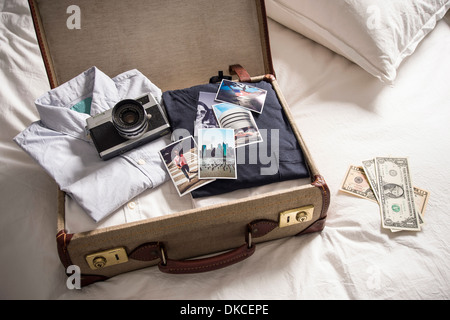 Valise ouverte sur le lit avec l'appareil photo et les photos Banque D'Images