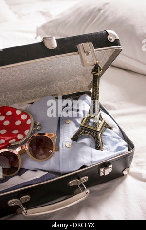 Valise ouverte sur le lit avec des lunettes de soleil et de souvenirs de la tour Eiffel Banque D'Images