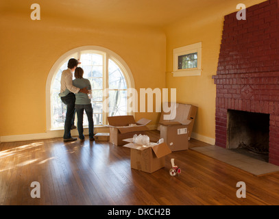 Un couple dans une chambre vide dans une maison d'habitation avec des boîtes en carton qui suggère qu'ils se déplacent vers l'intérieur ou l'extérieur. Banque D'Images