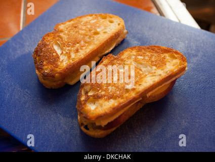 Sandwichs grillés au brie et aux poires sur une planche à découper en plastique. Banque D'Images