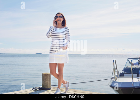 Young woman on cell phone on pier, Gavle, Suède Banque D'Images