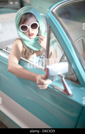 Femme au foulard et lunettes blanches en décapotable vintage Banque D'Images