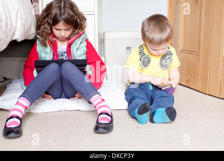 Les enfants à l'aide de tablette numérique et téléphone cellulaire Banque D'Images