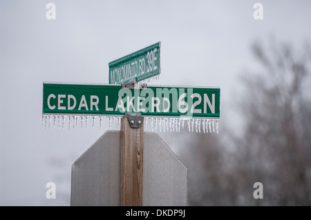 L'intersection des plaques de rue avec les gouttes gelés pendant du fond avec l'arrière d'un panneau d'arrêt. Mots sur le signe. Banque D'Images