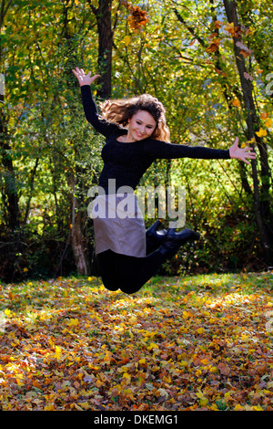 Femme sautant dans les feuilles d'automne Banque D'Images