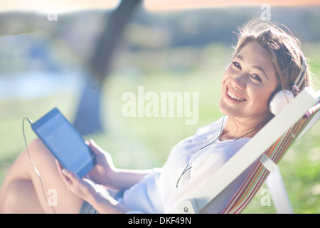 Jeune femme repose dans une chaise avec tablette numérique Banque D'Images