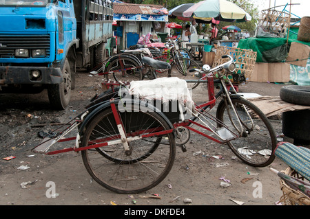 Une rangée de vieux vélos-taxis à trois roues stationné dans une zone délabrée de Yangon Myanmar Banque D'Images