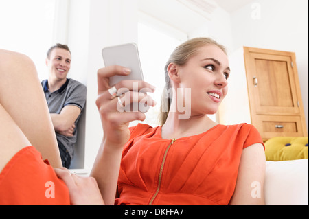 Deux jeunes adultes se prélasser dans la salle de séjour avec mobile Banque D'Images